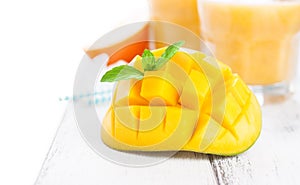 Fresh juicy summer cut mango, oranges and refreshment drinks on a wooden table on a white background,