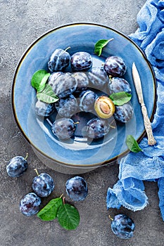 Fresh juicy sweet plums on plate with leaves