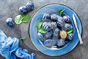 Fresh juicy sweet plums on plate with leaves