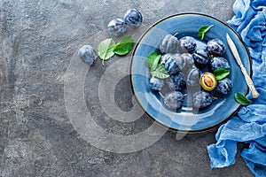 Fresh juicy sweet plums on plate with leaves