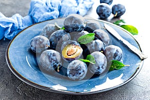 Fresh juicy sweet plums on plate with leaves