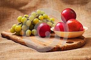 Fresh juicy white grapes and nectarines on a wooden board,