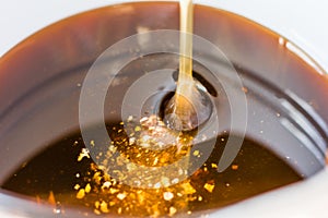 Fresh , just now collected honey is pouring into container