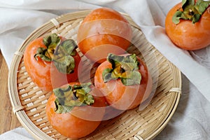 Fresh kaki on Chinese basket.Ripe orange persimmon fruit on white.