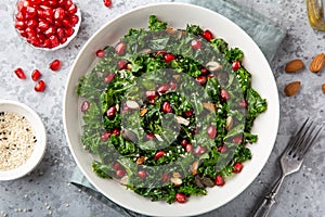 Fresh kale, roasted chickpeas, almond and pomegranate salad in white bowl