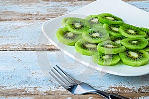 Fresh kiwi fruit in a plate on a wooden table.