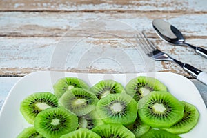 Fresh kiwi fruit in a plate on a wooden table.