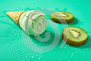 Fresh kiwi fruit slices and a kiwi fruit flavor ice cream cone on green background