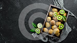 Fresh kiwi and green leaves in a wooden box on the old background. Fruits.