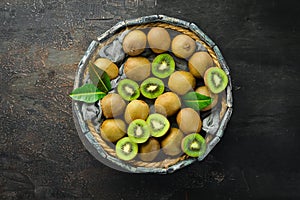 Fresh kiwi and green leaves in a wooden box on the old background. Fruits. Top view.