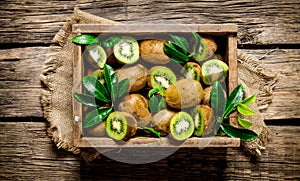 Fresh kiwi with leaves in an old box .