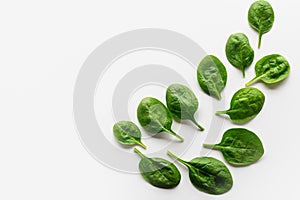 Fresh leaves of spinach are laid out on a white background in the form of a pattern