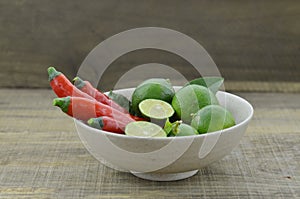 Fresh lemon cut half with chili in bowl on wooden background