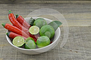 Fresh lemon cut half with chili in bowl on wooden background