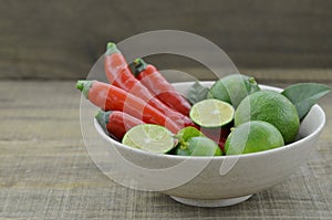 Fresh lemon cut half with chili in bowl on wooden table