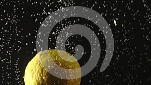 Fresh lemon falling into the water with bubbles on black background. Fresh berries in the water. Organic berry, fruit