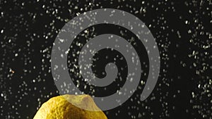 Fresh lemon falling into the water with bubbles on black background. Fresh berries in the water. Organic berry, fruit