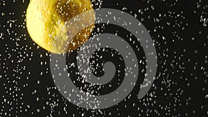 Fresh lemon falling into the water with bubbles on black background. Fresh berries in the water. Organic berry, fruit