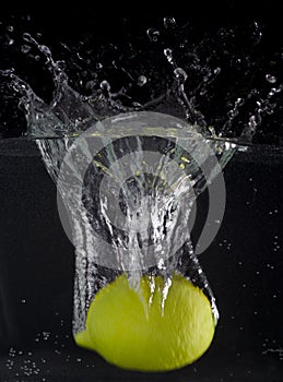 Fresh lemon falling into the water with a splash of water