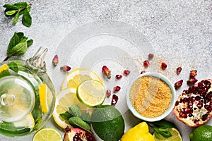 Fresh lemon, lime, pomegranate, dried tea rose flowers, tea, cane sugar, mint leaves and glass teapot on gray background. Ingredie