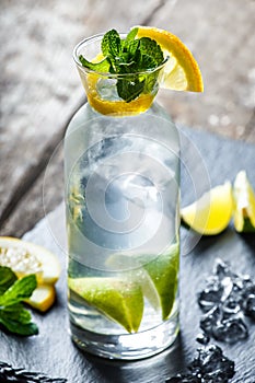 Fresh lemonade mojito with mint, lime and ice in glass on wooden background. Summer drinks and alcoholic cocktails