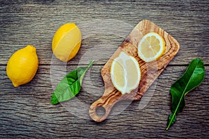 Fresh lemons and lemons leaves on rustic wooden background. Fre