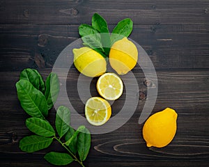 Fresh lemons and lemons leaves on wooden background