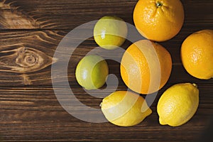 Fresh lemons, limes and oranges on brown wooden table. Juicy fruits.