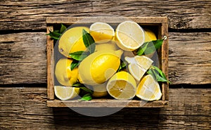 Fresh lemons in an old box with leaves.