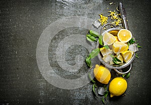 Fresh lemons in a saucepan with leaves and zest.