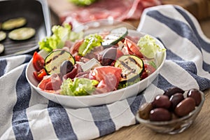 Fresh lettuce salad with grilled zucchini coppa di parma ham feta cheese olives tomatoes and olive oil