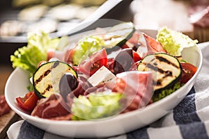 Fresh lettuce salad with grilled zucchini coppa di parma ham feta cheese olives tomatoes and olive oil