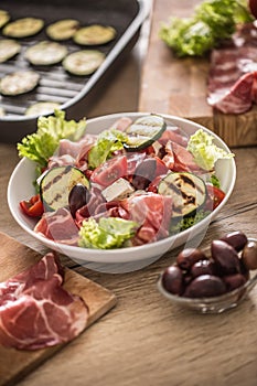 Fresh lettuce salad with grilled zucchini coppa di parma ham feta cheese olives tomatoes and olive oil