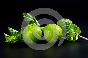 Fresh lime fruits and mint leaves on a black background. Citrus fruit