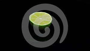 Fresh lime rotating in a circle, black background, and space for text. Reflection.