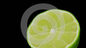 Fresh lime rotating in a circle, black background, and space for text. Reflection.