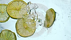 Fresh lime slices falling water close up. Juicy pieces acidic citrus floating.