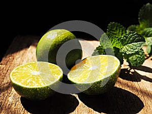 Fresh limes sliced in half on vintage wooden background.