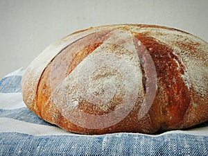 Fresh loaf of bread on handmade striped linen towel.
