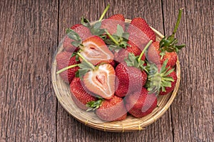 Fresh long stem Strawberry in Bamboo basket, Red Strawberries in wooden bowl on wooden table.