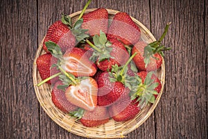 Fresh long stem Strawberry in Bamboo basket, Red Strawberries in wooden bowl on wooden table.