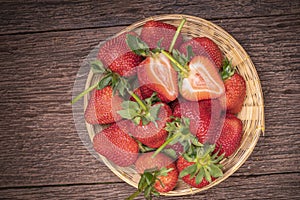 Fresh long stem Strawberry in Bamboo basket, Red Strawberries in wooden bowl on wooden table.