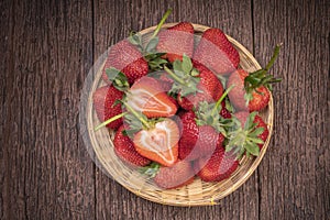 Fresh long stem Strawberry in Bamboo basket, Red Strawberries in wooden bowl on wooden table.