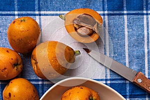 Fresh loquats medlars on blue checkered tablecloth background Rustic and healthy appearance. Close-up.Top view
