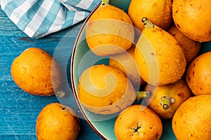 Fresh loquats medlars in blue turquoise bowl. Rustic and healthy appearance.