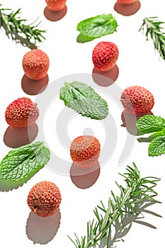 Fresh lychee fruits with rosemary and mint leaves on white background. Minimal style composition. Healthy food concept. Summer