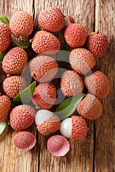 Fresh lychee and peeled showing the red skin and white flesh with green leaf. Vertical top view