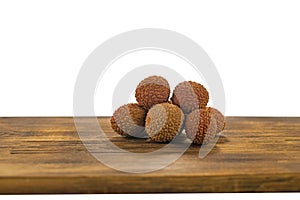 Fresh lychee and peeled showing the red skin and white flesh with green leaf on a wooden background. Lychi with leaves - tropical photo