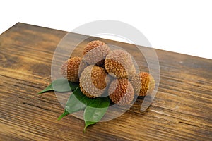 Fresh lychee and peeled showing the red skin and white flesh with green leaf on a wooden background. Lychi with leaves - tropical photo