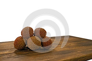 Fresh lychee and peeled showing the red skin and white flesh with green leaf on a wooden background. Lychi with leaves - tropical photo